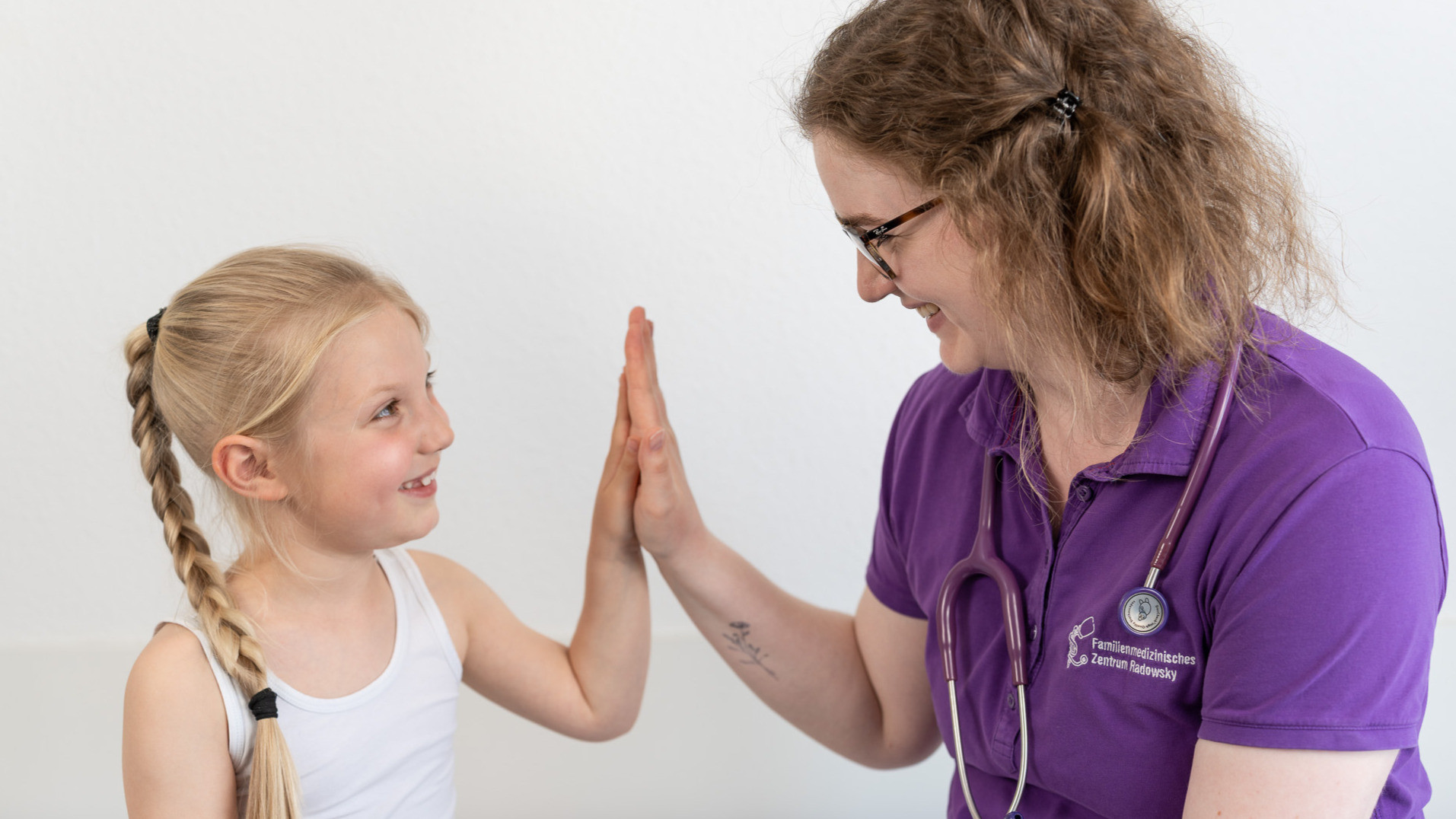 junges Mädchen und Ärztin legen Handflächen zusammen und lächeln